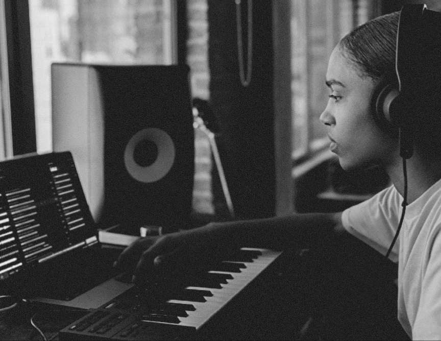 Producer wearing headphones playing a MIDI keyboard
